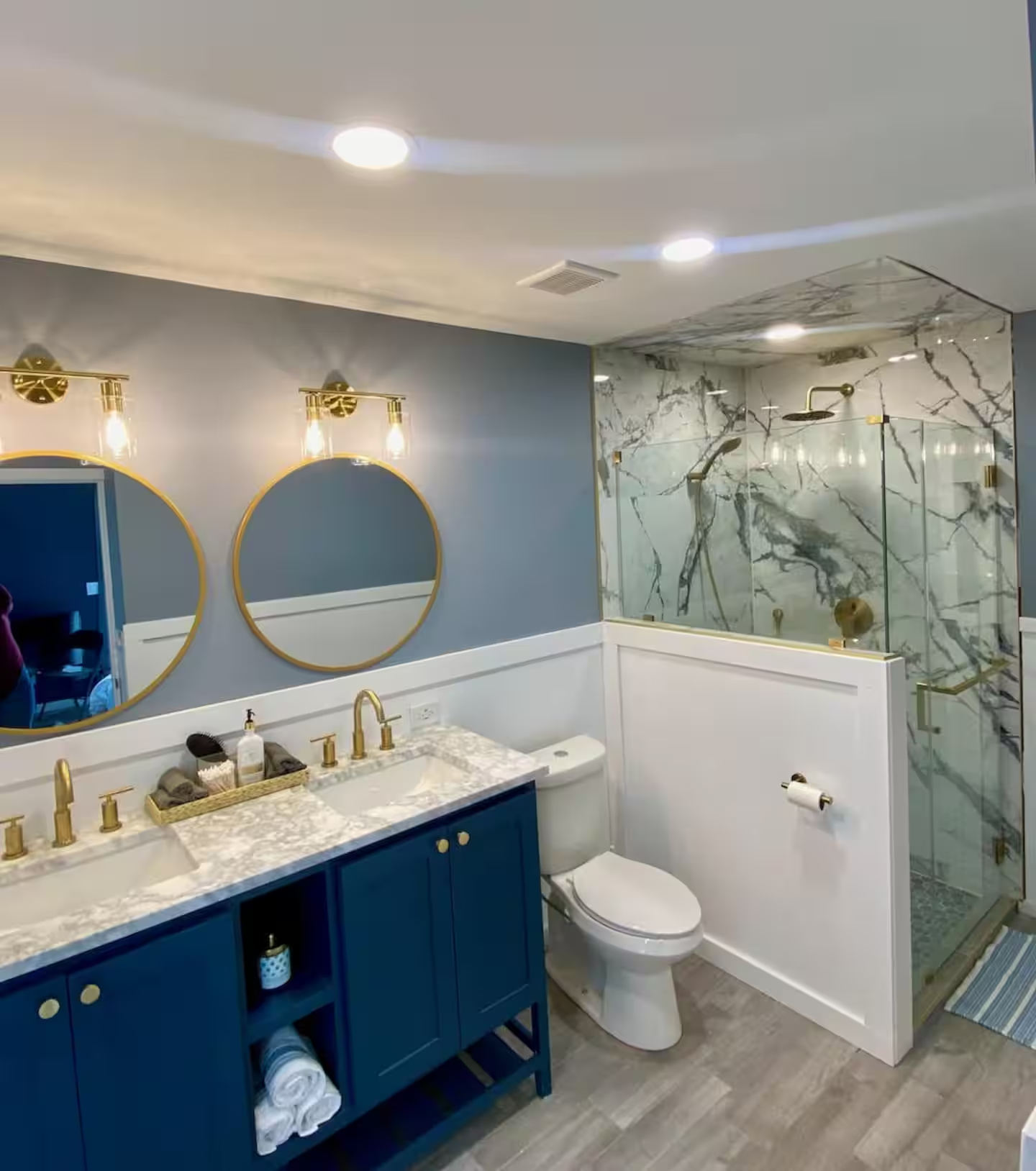 Renovated bathroom with double vanity, gold fixtures and marble shower